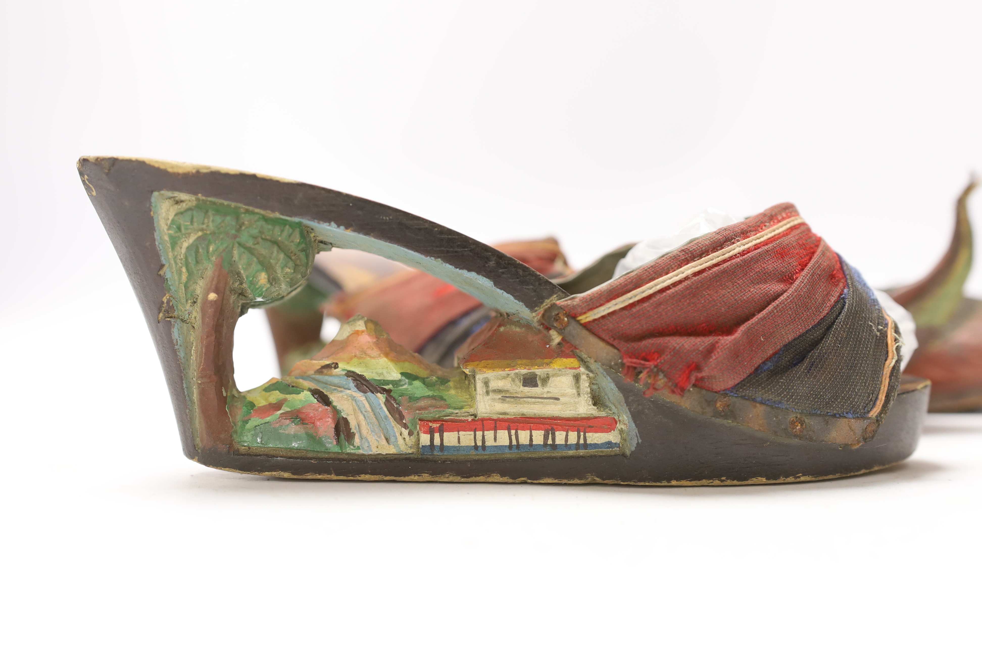 Two pairs of shoes; a small pair of novelty carved wooden heeled clogs with Philippine’s 1945 painted on the back of the heels and a carved house and mountainous scene within the heel and sole, together with a pair of le